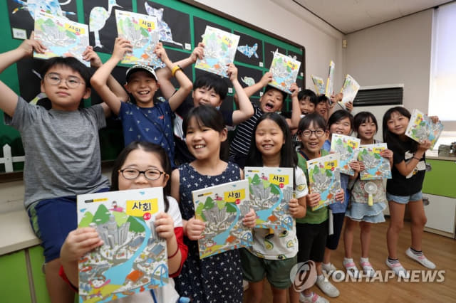 한 초등학교 학생들이 새로 받은 교과서를 들어보이고 있다./연합뉴스/