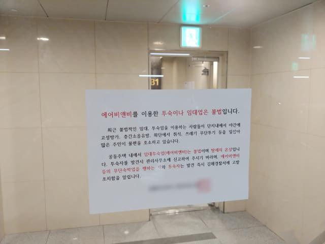 21일 오전 김해시의 한 아파트 입구에 공유숙박 경고문이 붙어 있다.