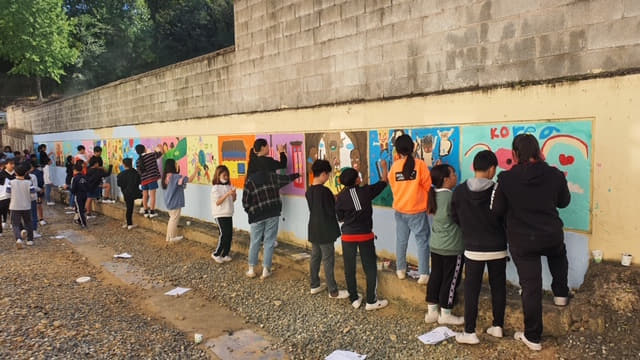 함안 칠서초등학교가 추진한 도나온 벽화 그리기 프로젝트에 참여한 학생과 교직원 모습./함안교육지원청/
