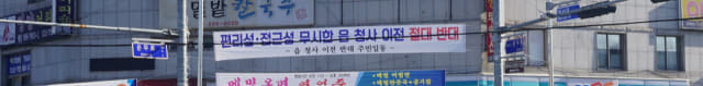 15일 함안군 칠원읍사무소 앞 상가 건물에 새 청사 이전 건립을 반대하는 플래카드가 붙여져 있다./김호철 기자/