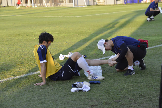 경남FC 김용훈 트레이너가 발목에 부상을 입은 선수의 발에 테이프를 감고 있다.