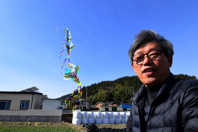윤종민 씨가 자신의 연 공방 옆 들에서 3m 가격으로 120개를 연결해 길이 400m에 이르는 창작연을 날리고 있다.