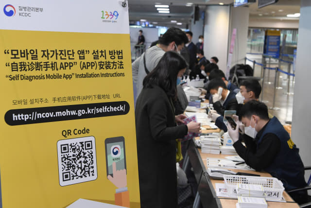 중국과 홍콩, 마카오에 대한 특별입국절차가 개시된 13일 인천국제공항에서 홍콩 발 항공편 승객들이 '자가진단 앱' 설치를 하고 있다. 연합뉴스