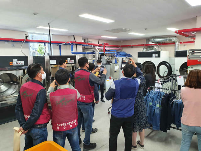 타 지역 지자체·기관 관계자들이 김해 노동자 작업복 세탁소를 찾은 모습./김해시/