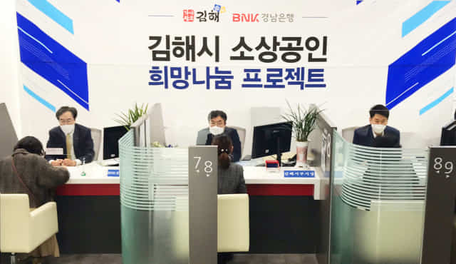 BNK경남은행 예경탁 상무와 김해시 강덕출 부시장이 지역 소상공인들에게 금융상품 상담과 경영컨설팅을 하고 있다.