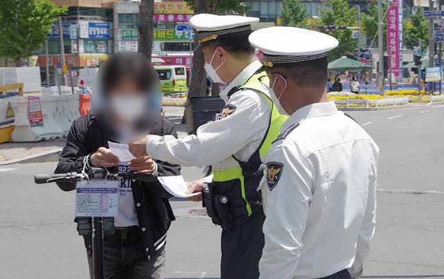 13일 오후 경남대학교 앞에서 경찰이 안전모를 착용하지 않고 전동킥보드를 이용한 시민을 적발해 계도하고 있다.