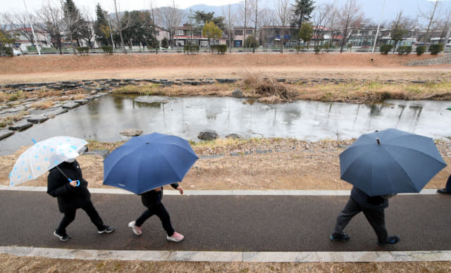 창원시 성산구 창원천 산책로에 우산을 든 시민들이 산책을 즐기고 있다./경남신문 자료사진/