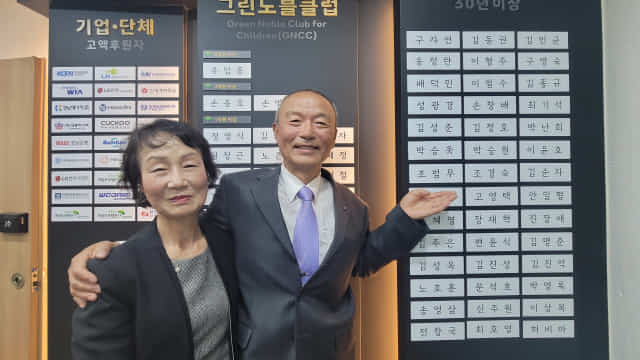 조범무씨가 아내 이혜란씨와 초록우산 어린이재단 명예의 전당에 오른 자신의 명패 옆에서 기념촬영을 하고 있다.