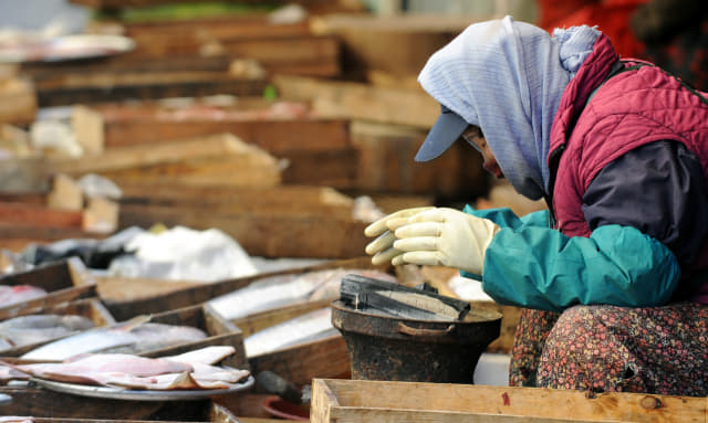2012년 2월 마산어시장 상인이 두터운 옷을 입고 화로에 손을 녹이고 있다.