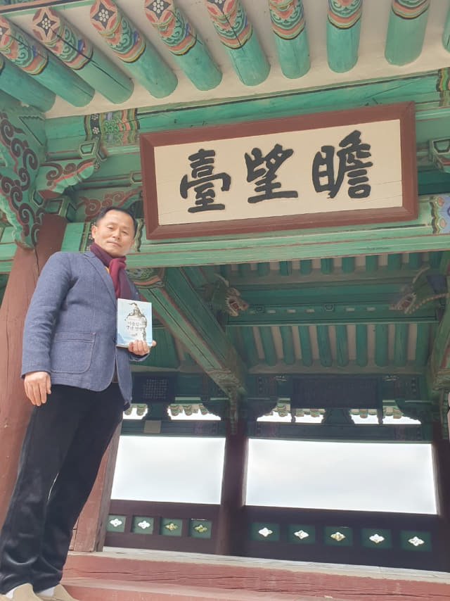 서홍교 작가가 ‘이순신순국공원’에 있는 첨망대에서 자신의 저서 ‘아직도 끝나지 않은 이순신의 7년 전쟁’을 들고 기념촬영을 하고 있다.