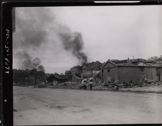 1950년 9월 15일 인천 시내에서 폭격으로 부서지고 불타고 있는 건물을 주민들이 지나고 있다./미국 국립문서기록관리청 NARA 발굴·전갑생 제공/