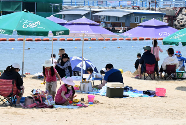 21일 오후 창원시 마산합포구 광암해수욕장을 찾은 시민들이 비치 파라솔 아래에 앉아 때이른 더위를 식히고 있다./성승건 기자/