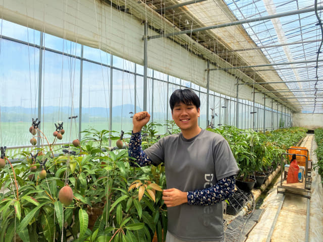 김성우 대표가 창원시 의창구 동읍 산남리 자신의 스마트팜 애플망고 농장에서 파이팅을 하며 환하게 웃고 있다./창원시/