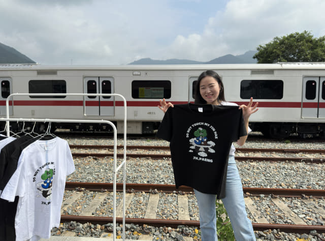 김경옥 W콘텐츠랩 대표가 진해 팽나무 티셔츠를 들고 사진을 찍고 있다.