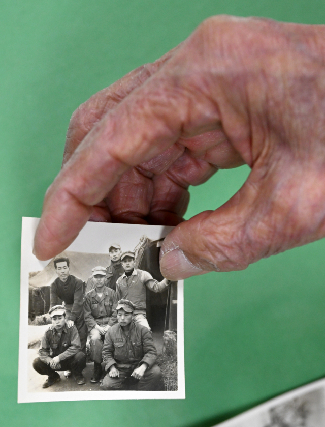 김종갑씨(맨 왼쪽 위)가 1954년 1사단에서 근무할 당시 전우들과 찍은 단체 사진을 보여주고 있다.