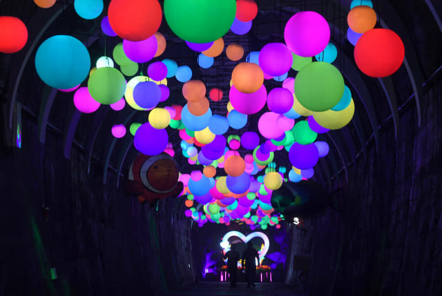 밀양 트윈터널을 찾은 관광객들이 색색의 등이 달린 ‘차원의 길’을 지나고 있다./김승권 기자/