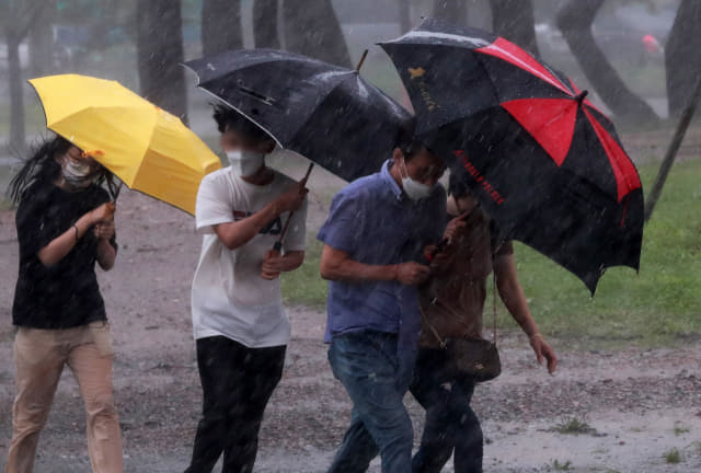 태풍 장미가 상륙한 10일 오후 부산 해운대 해수욕장 부근에서 시민들이 비바람을 피해 우산을 쓰고 걸어가고 있다. 연합뉴스