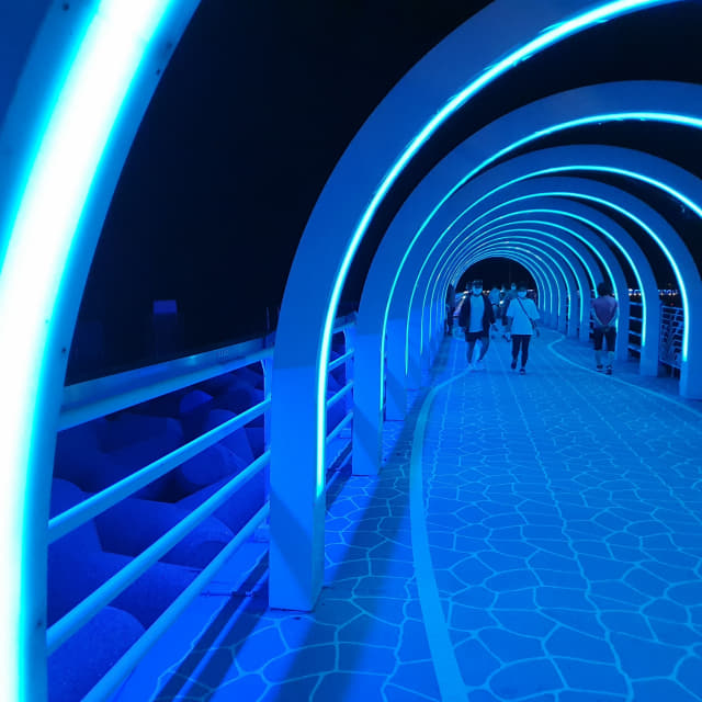 광암방파제 불빛거리 빛터널을 주민들이 걷고 있다.