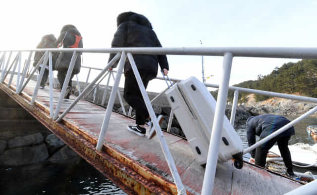 A equipe médica que embarcou em um barco adicional e desembarcou no píer na vila de Onpo, em Saryangdoo, entrou na vila com uma sacola cheia de remédios.  / Repórter Seong Geun Seung /