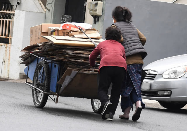 14일 창원의 한 주택가에서 한 시민이 손수레에 폐지를 가득 싣고 가는 할머니를 돕고 있다./김승권 기자/